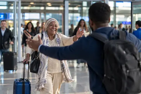 A mother walking out of Arrivals with open arms
